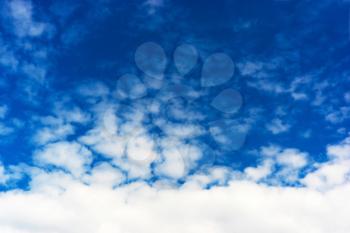 Horizontal bottom aligned white cloudscape on blue sky background