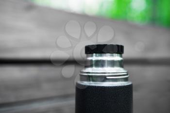 Horizontal black and white thermos with green bokeh background