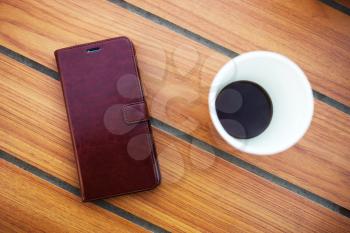 Wooden table in cafe with cell phone and coffee background
