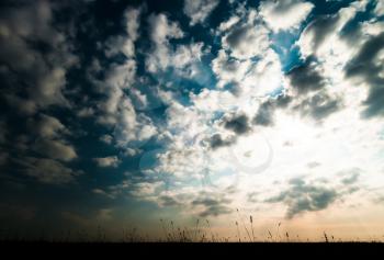 Horizontal ground silhouette with dramatic clouds and sunshine background backdrop