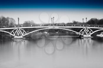 Black and white dramatic arc bridge in Moscow park with blue sky background