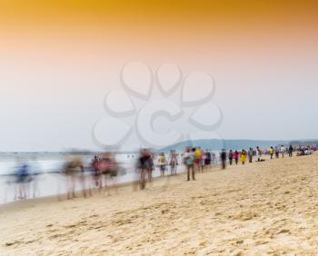 Horizontal vivid vibrant sunset on Indian beach with crowd of people in motion abstraction background backdrop