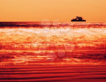 Horizontal vivid orange ship silhouette in ocean blurred background