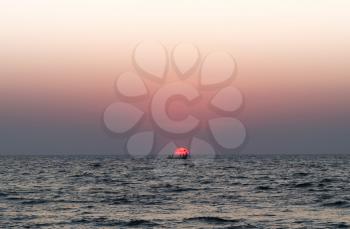 Solar disk boat people ocean sunset