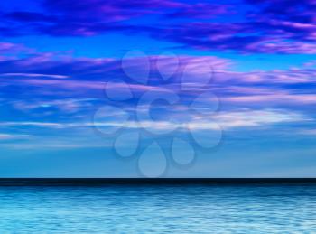 Horizontal vibrant ocean horizon with dramatic cloudscape background backdrop