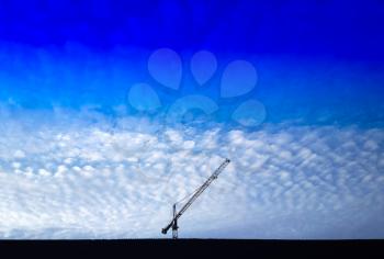 Building crane below fleecy clouds background hd