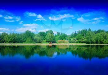Summer park on river with dramatic reflections background