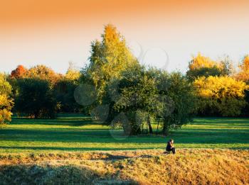 Sitting traveller in autumn park landscape background