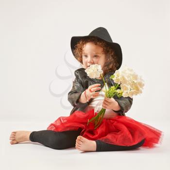 Little girl with black hat and flowers sitting and dreaming