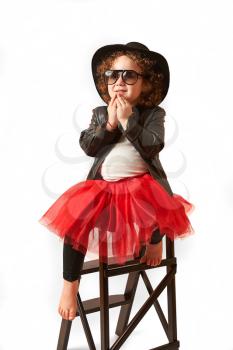 Little girl with black hat sitting on a high stool and thinking
