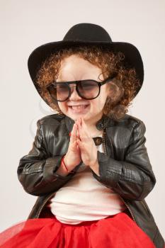 Little girl with black hat and Sunglasses sitting and smiling