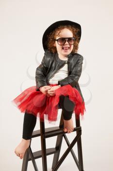 Little girl with black hat sitting on a high stool and dabbles