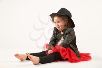 Little girl with black hat sitting and looking up