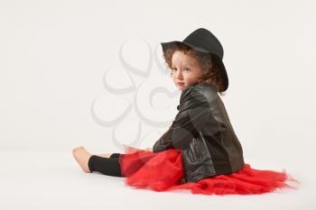 Little girl with black hat sitting and thinking
