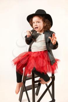 Little girl with black hat and sunglasses sitting and thinking