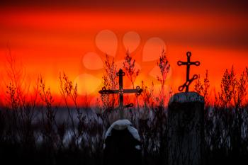 Christian cross silhouette with the bloody sunset as background