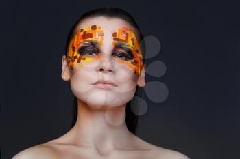 Portrait of a girl with an original make-up. Beauty close-up with orange and red rhinestones on a face of the model
