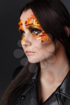 Portrait of a girl with an original make-up. Beauty close-up with orange and red rhinestones on a face of the model