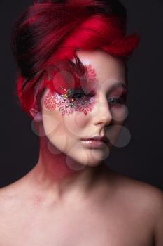 Portrait of a beauty young  girl with red hair.  Creative ingenious makeup with feathers, rhinestones and large eyelashes