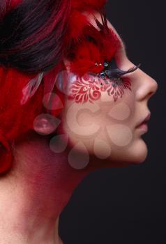 Portrait of a beauty young  girl with red hair.  Creative ingenious makeup with feathers, rhinestones and large eyelashes