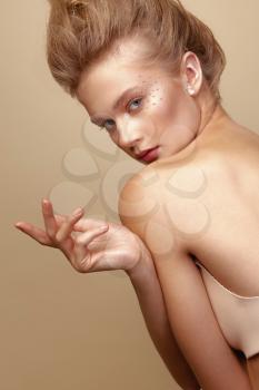 Studio Portrait of a young cute blonde model girl in art makeup with rhinestones
