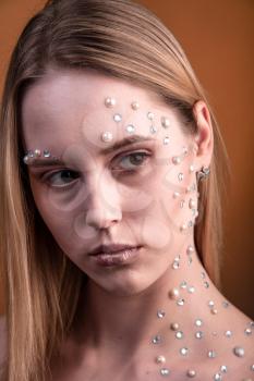 Portrait of a girl with original and creative makeup with white and pearl rhinestones