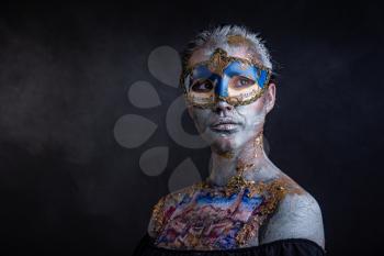Portrait of a young masked woman with creative makeup on the theme of Venice Carnival