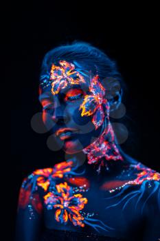 Conceptual face art with shining flowers painted in fluorescent colors isolated on black background