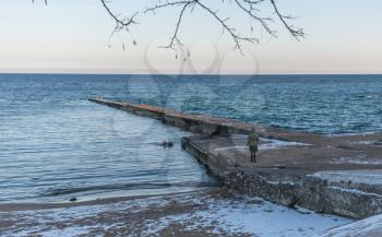 Odessa, Ukraine - 12.27.2018. Lonely people on the pier by the sea on a sunny winter day