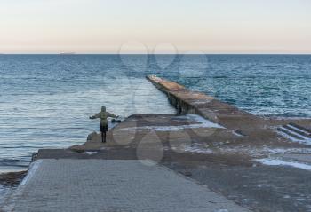 Odessa, Ukraine - 12.27.2018. Lonely people on the pier by the sea on a sunny winter day