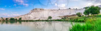 Pamukkale, Turkey – 07.15.2019. White mountain and green lake in Pamukkale. Panoramic view from the side of the village on a summer morning