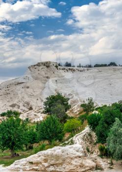 Pamukkale, Turkey – 07.14.2019. Many tourists on Pamukkale white Mountain. Panoramic view from the side of the village on a cloudy summer evening.