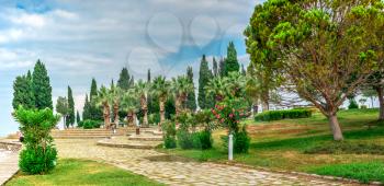 A path in a small park with a viewing platform on top of the white Pamukkale mountain near travertines on a summer morning.