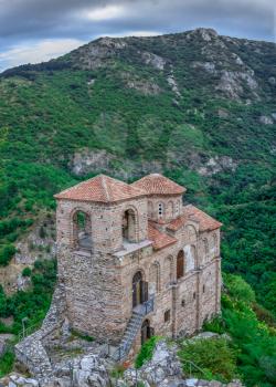 Asenovgrad, Bulgaria 24.07.2019. Church of the holy mother of God in the Asens Fortress surrounded Bulgarian Rhodope mountains on a cloudy summer day