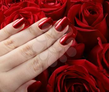 Red metallic manicure over the roses background.