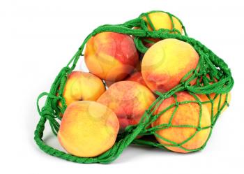 The peaches in a green string bag isolated on white background