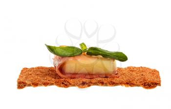 Parma ham with melon and basil on a rye crisp isolated on white background