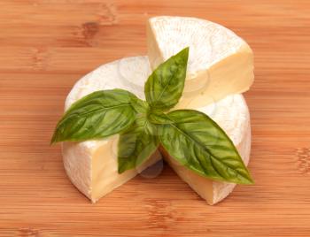 Brie cheese with a basil on the bamboo chopping board