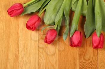 Bouquet of red tulip flowers on the oak flooring
