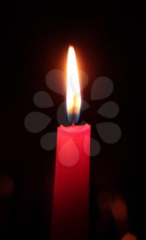Single red candle on a black background