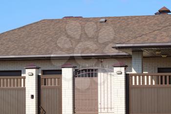 Facade of housing in the same style. Beautiful tile on the roof and the fence brown.