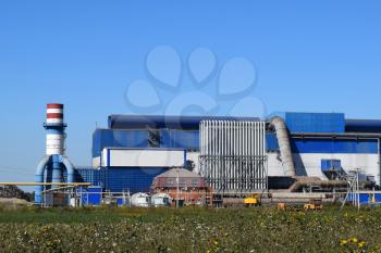 Big plant for processing scrap metal. Huge factory old metal refiner. Blue roof of the factory building. Exhaust pipes, radiators, cooling industrial units as well as office buildings.