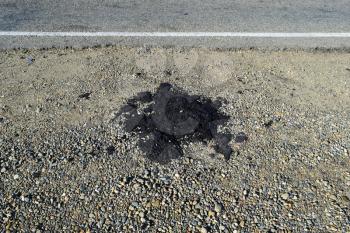 The piece of fresh asphalt which dropped out on a roadside. Repair of the road.