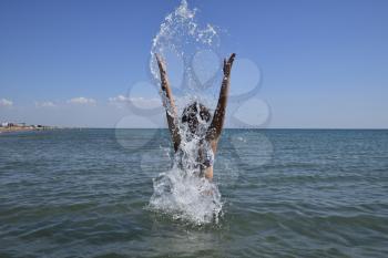 She sprinkles in seawater. Flying up spray from the water throws. The girl with dark hair and a bathing enjoys sea.