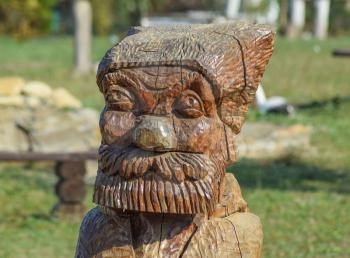 The face of a bearded old man carved out of logs. Wooden idol.