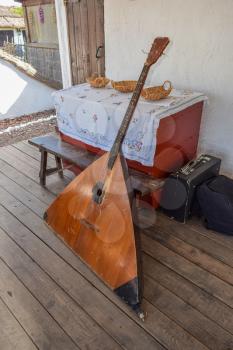 Balalaika-contrabass under a canopy in a cottage. Bass balalaika rare instrument.