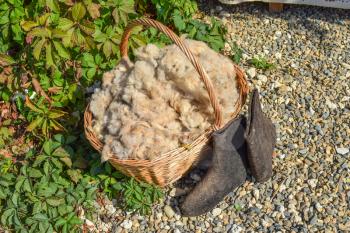The wool in the basket and black boots. Sheared from sheep wool.