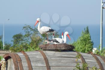Toy nest of a stork with birds on it. Artificial images of fauna.