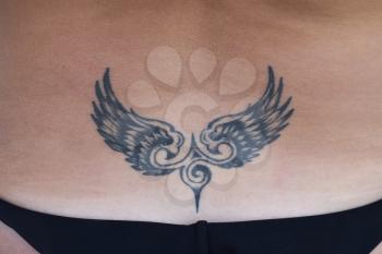 The tattoo in the shape of wings on the back. Simple tattoo for female body decoration.