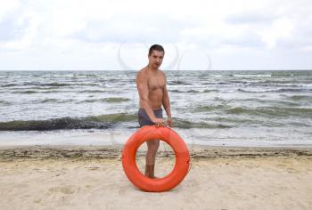 The man on the beach with a lifebuoy. Safety beach holiday at sea. Man with a life buoy on the beach. Rescue and safety on the water.